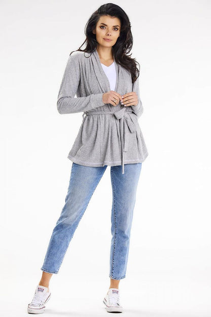 Chic grey loose-fit cardigan with belt and shawl collar, elegantly worn over a white top and blue jeans, ideal for a stylish evening look by awama.