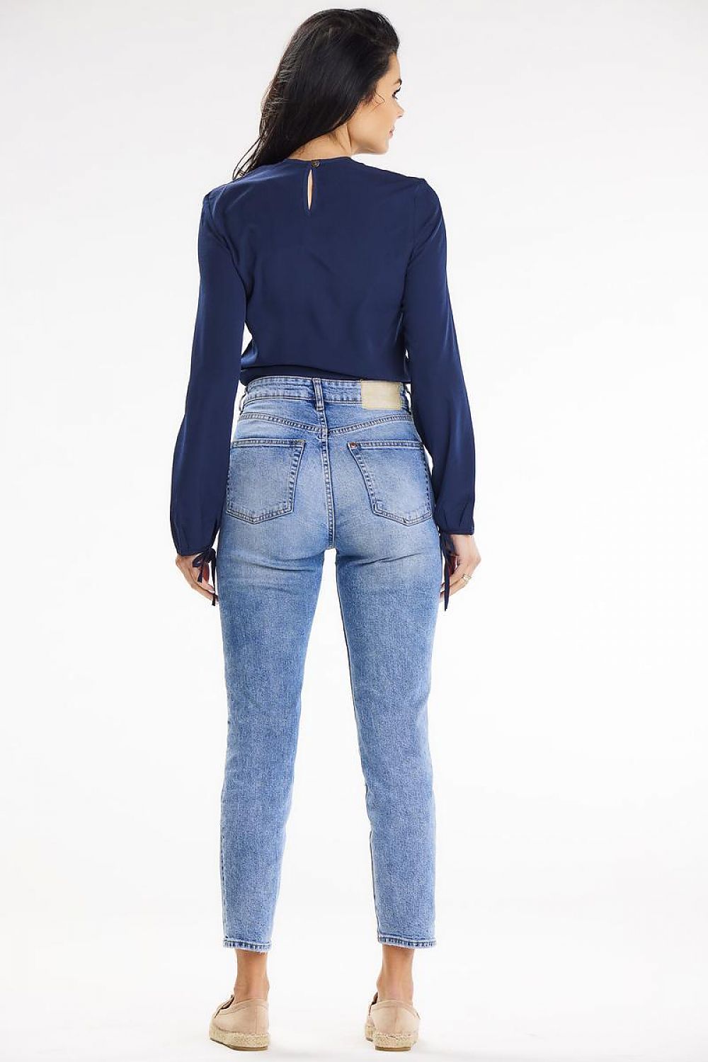 Rear view of a model wearing an elegant navy casual blouse with long sleeves and back button closure, styled with high-waisted jeans, crafted by Awama.