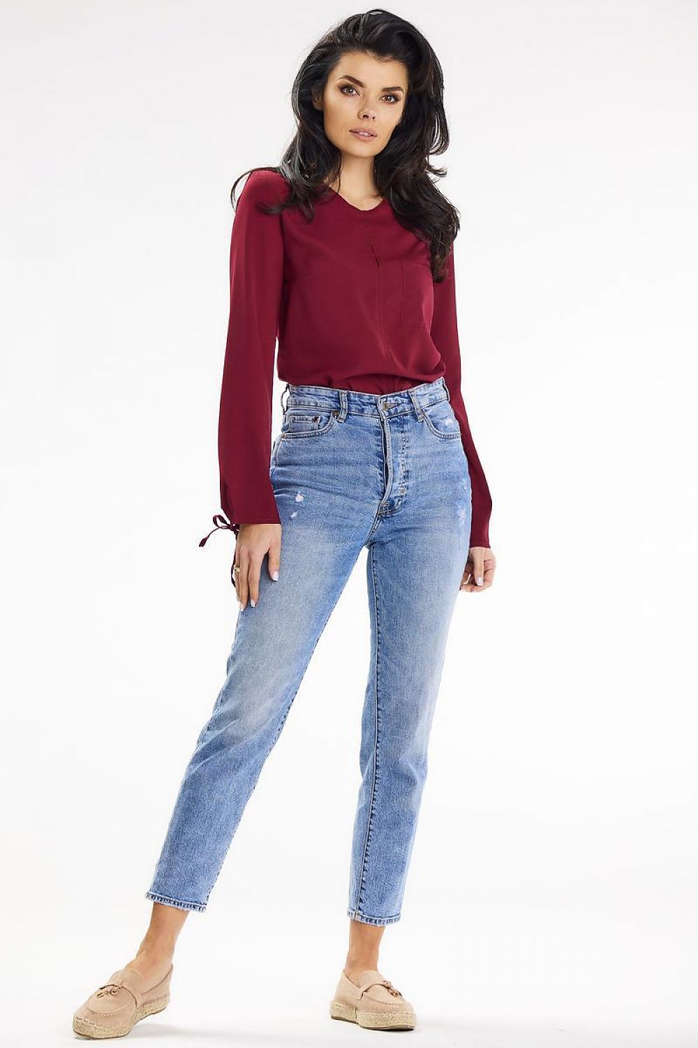 Model showcasing an elegant burgundy long-sleeve blouse with button closure from Awama, paired with classic blue jeans for a chic casual look.