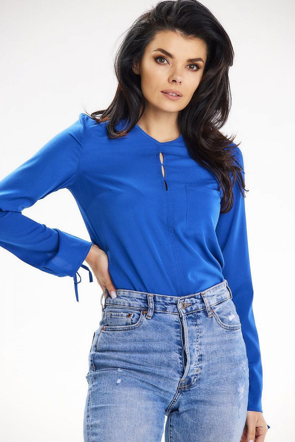 Close-up of a model wearing a sophisticated blue blouse with decorative slits at the neckline, designed by Awama, complemented by high-waisted distressed jeans.