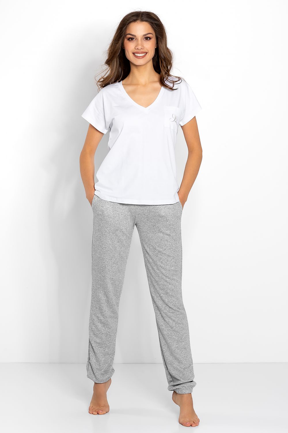 Momenti Per Me Elegant Chill Out Pyjama Set featuring a refined white V-neck T-shirt with a stylish silver emblem and soft grey knit trousers, presented in a luxurious setting.
