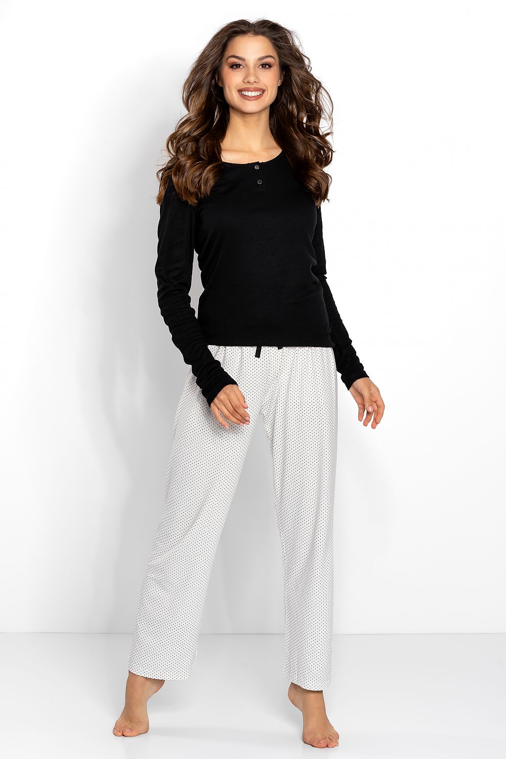 Elegant women's black and ecru pyjama set featuring a classic long sleeve top and stylish loose-fit trousers with a black bow detail at the waist. Perfect for luxury lounging.