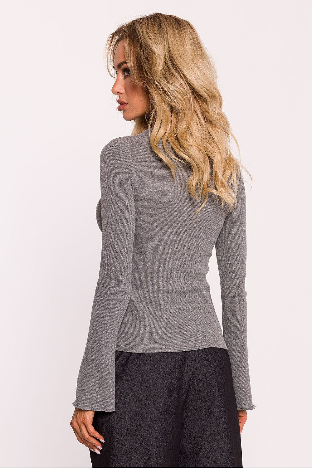 Close-up view of Moe's elegant ribbed cotton knit blouse, highlighting the intricate decorative stitching on the fitted long sleeves.