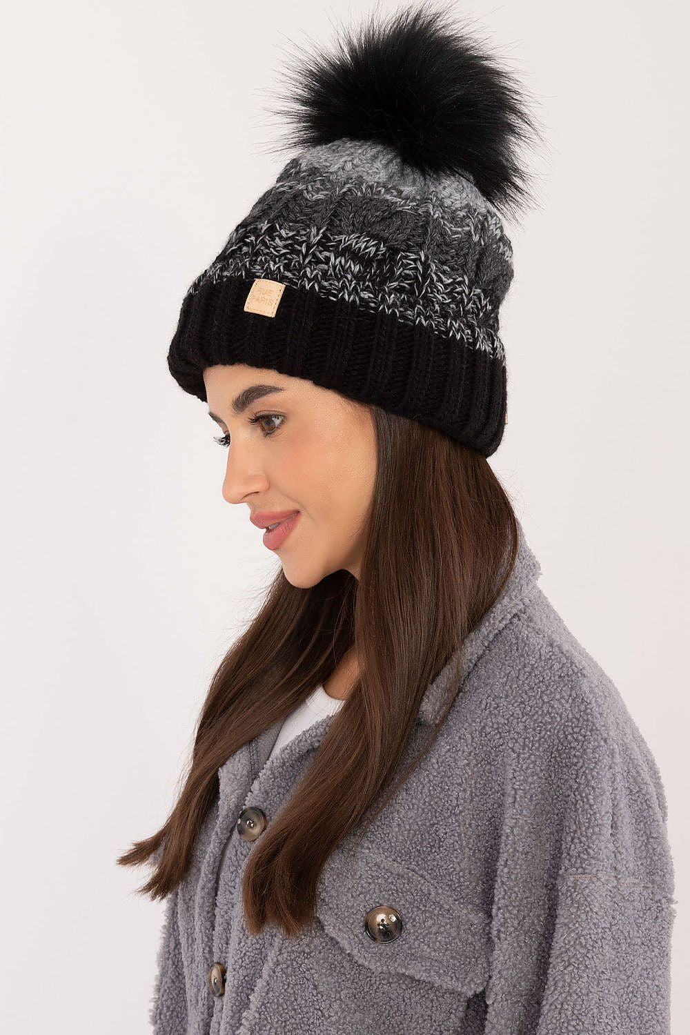 Side view of the sophisticated Rue Paris winter beanie adorned with a playful pom-pom, perfect for enhancing chic winter outfits.