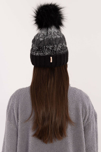 Model wearing a stylish Rue Paris winter beanie, combining elegance and comfort, showcasing its beautiful plaid pattern and fluffy pom-pom.
