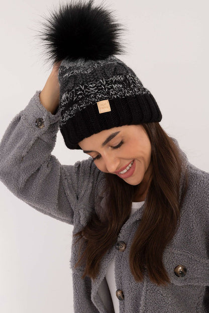 Elegant winter beanie by Rue Paris featuring a stylish plaid pattern and fluffy pom-pom, perfect for luxury winter looks.