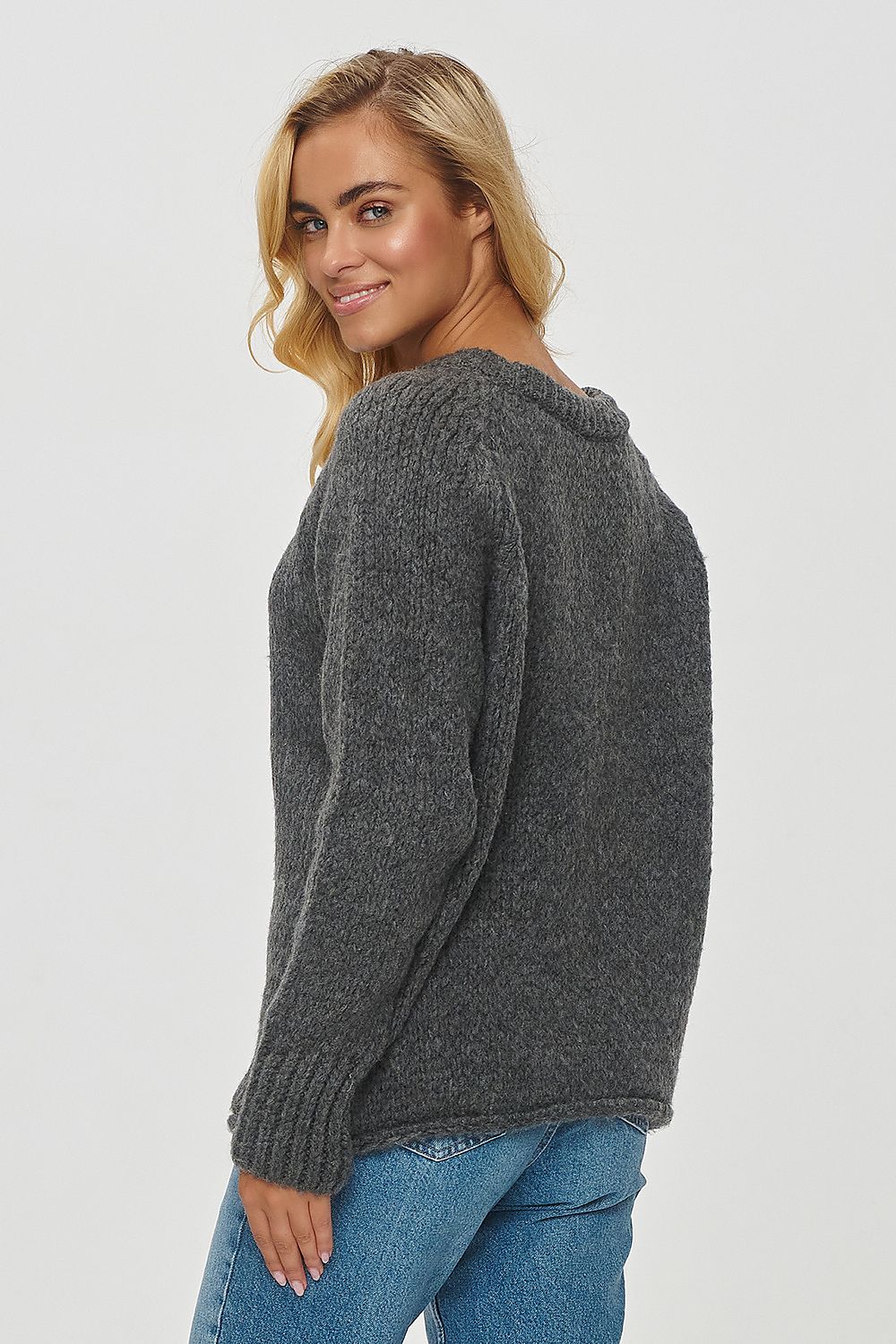 Model wearing the Makadamia luxurious loose-fitting sweater with round neckline and long sleeves, paired stylishly with jeans and sneakers for a refined casual look.