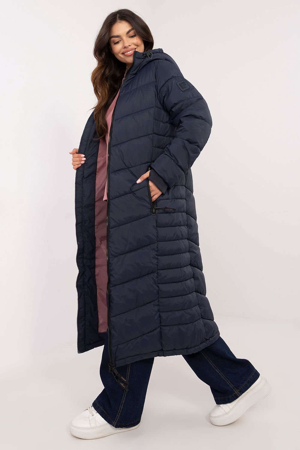 Stylish long women's coat by Sublevel displayed in a chic outdoor setting, highlighting its minimalist design and sophisticated style.