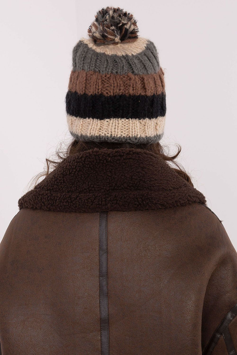 Luxurious winter beanie from AT, showcasing colorful stripes and a plush pom-pom for fashionable winter comfort.