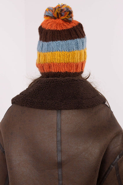 Sophisticated winter beanie by AT, combining vibrant stripes with a plush pom-pom, ideal for cold weather style.