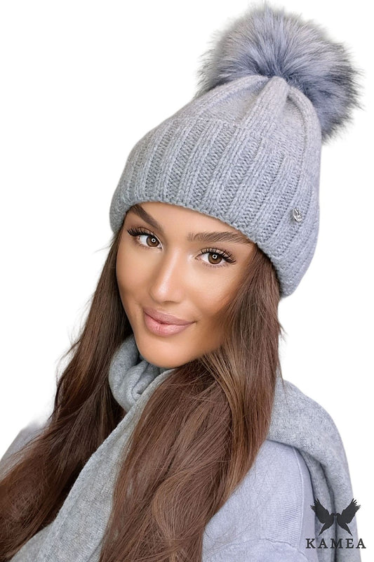 Elegant pink women's wool hat by Kamea featuring a fluffy pompom and luxurious silver emblem, perfect for winter style and warmth.