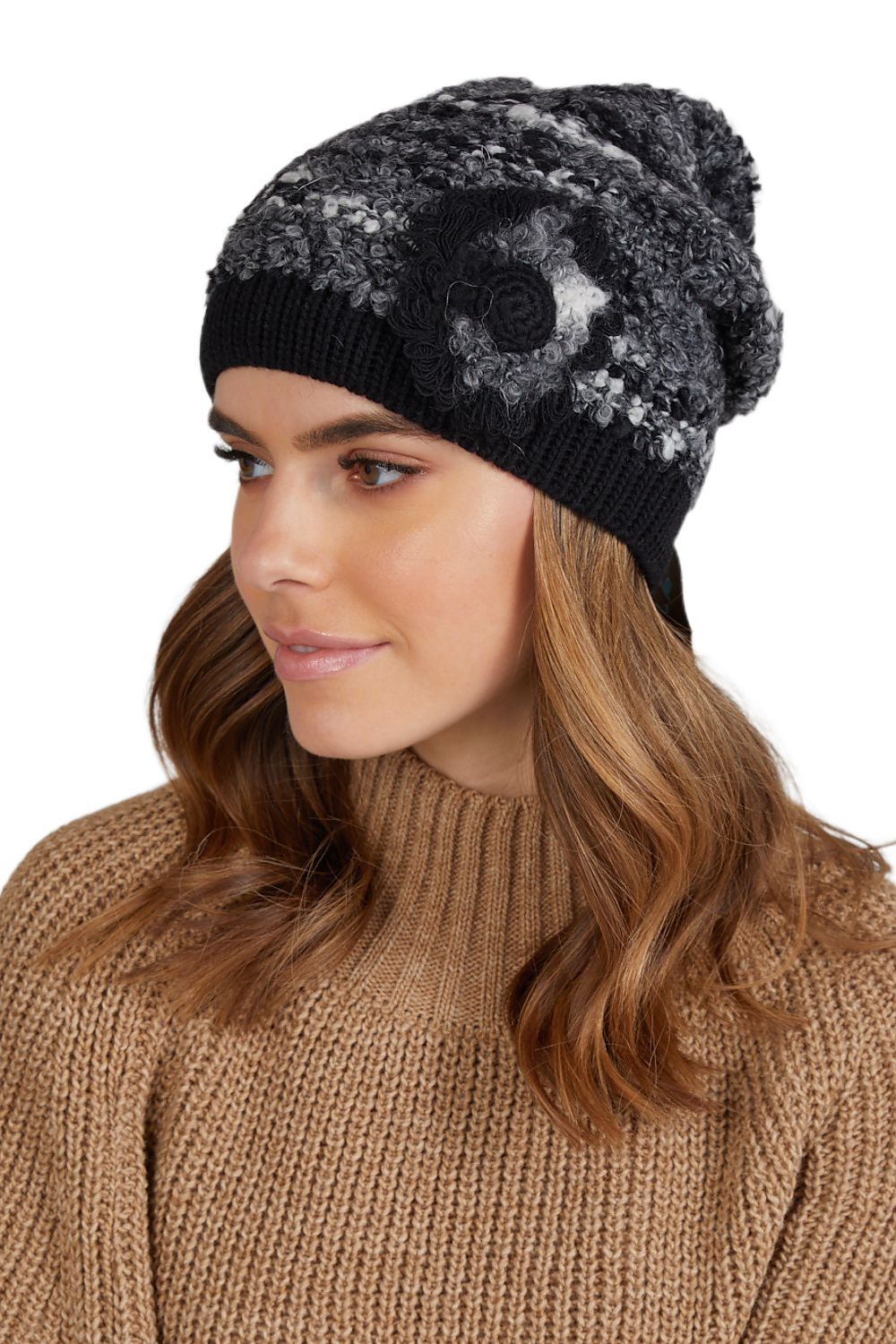 Premium black women's winter hat by Kamea, featuring a handmade crochet flower appliqué, crafted from soft two-tone bouclé for warmth and elegance.