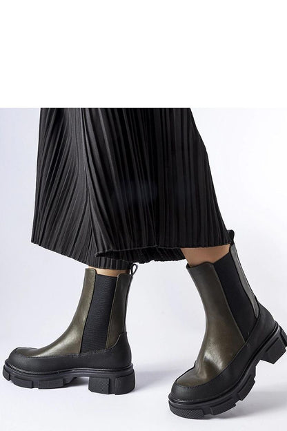 Solea Women's green and black Faisal Slip-On Boots displayed against a luxurious backdrop, highlighting their fashionable design and eco-friendly materials.