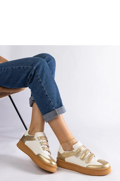 Solea's fashionable golden low sneakers on a stylish backdrop, perfect for enhancing both casual and elegant looks.