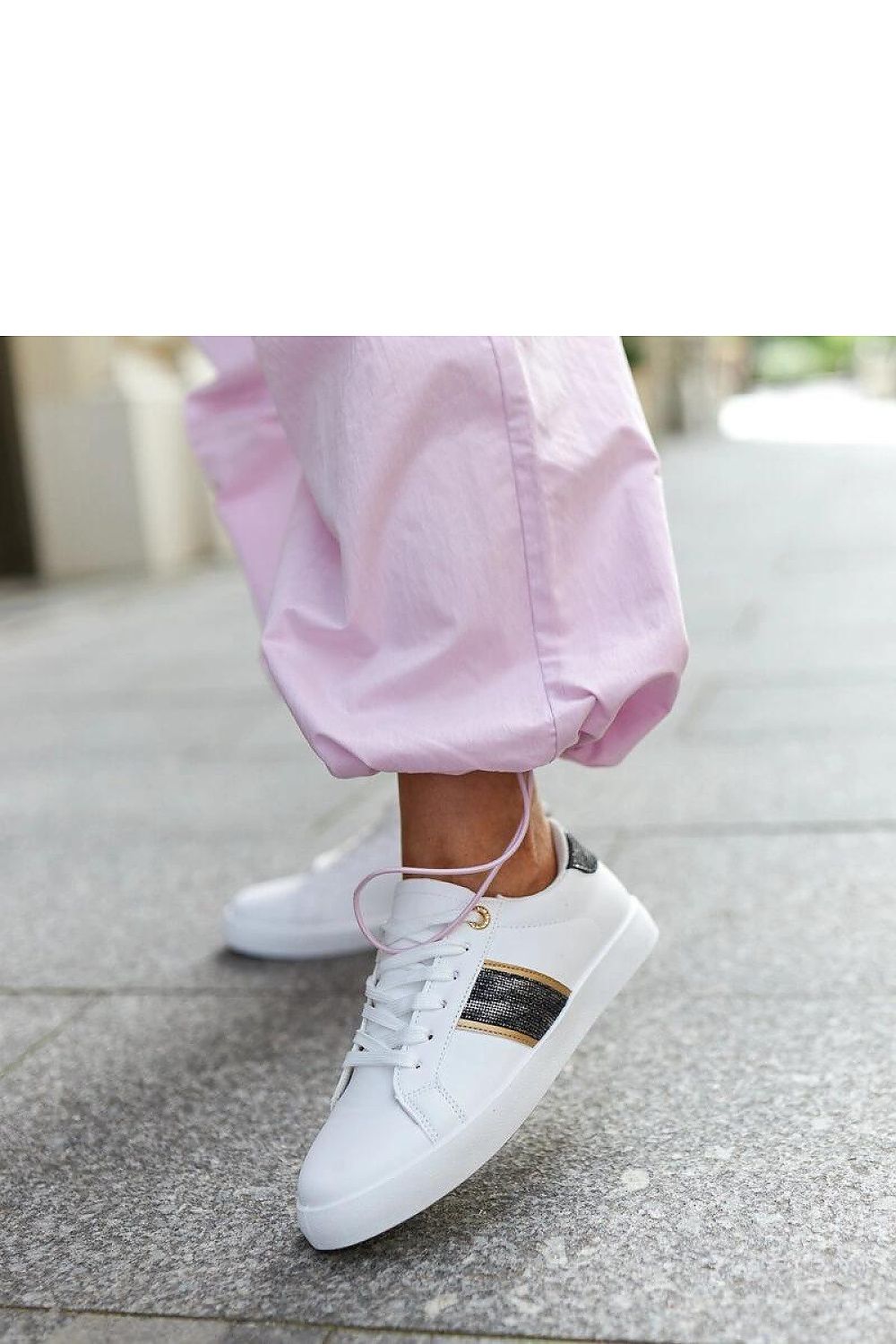 Close-up of Solea white and gold women’s sneakers showcasing exquisite zircons on a decorative strap.