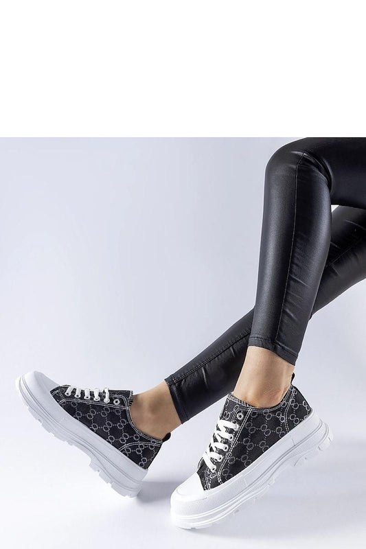 Close-up of Solea's luxurious black sneakers showcasing the Antonella monogram and elastic rubber sole for ultimate comfort and style.