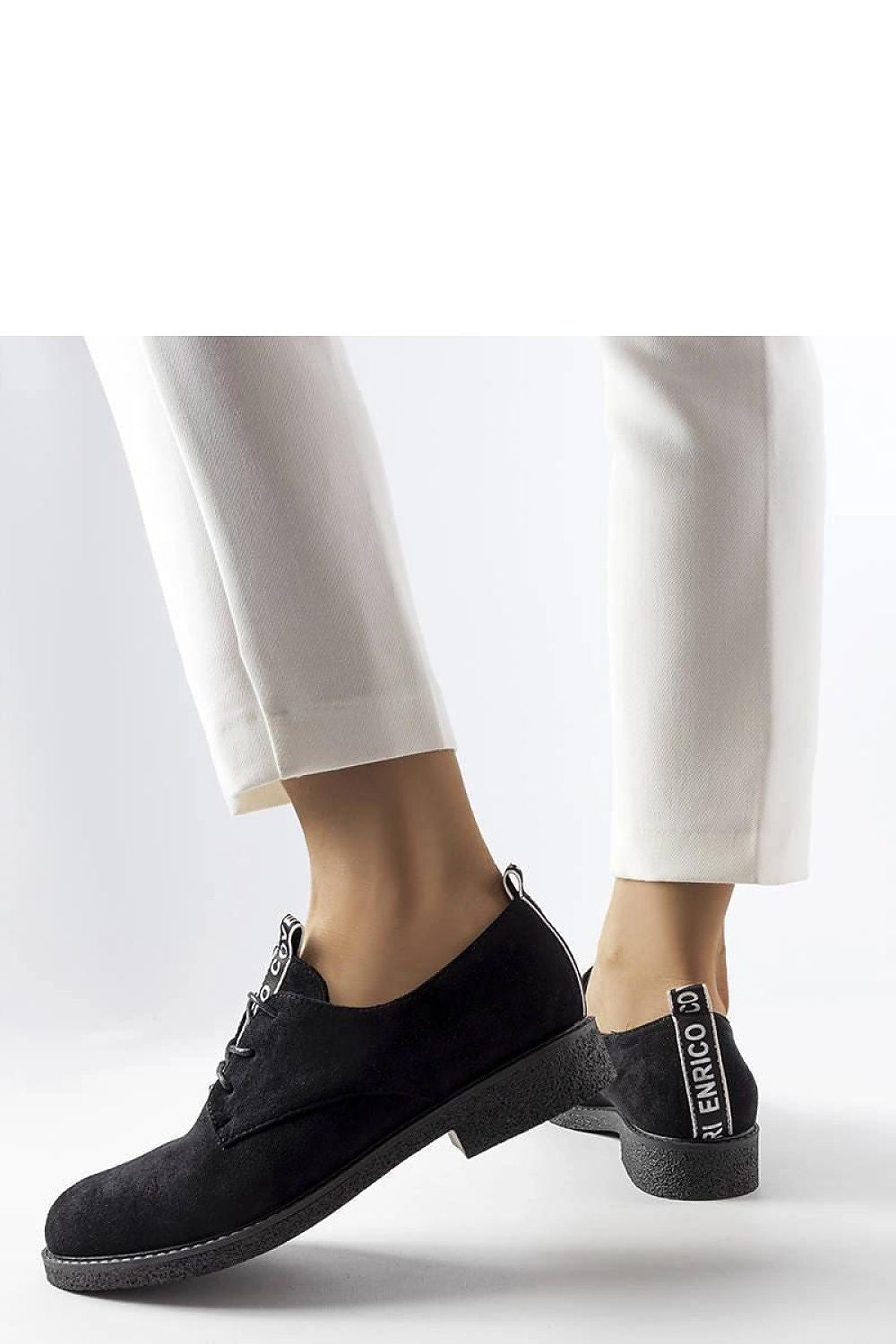 Model wearing Solea Eco-Suede Sneakers in chic black, paired with fashionable attire for a sophisticated look, available in US Sizes 5.5-10.5.