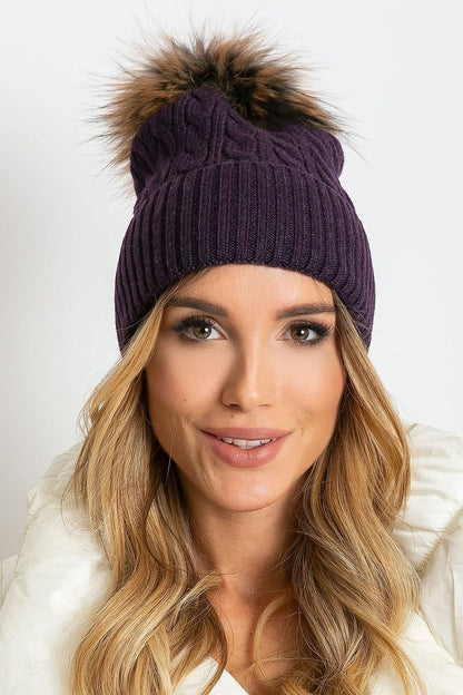 Luxury winter cap with wide cuff and fluffy pompom by AT, crafted from 50% acrylic, 30% cotton, and 20% cashmere, perfect for stylish cold weather outfits.