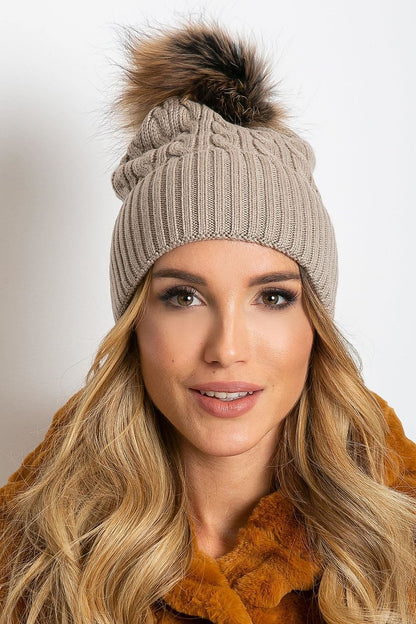 Trendy winter cap from AT featuring a fluffy pompom and a broad cuff, made with a luxurious blend of acrylic, cotton, and cashmere, designed for warmth and elegance.