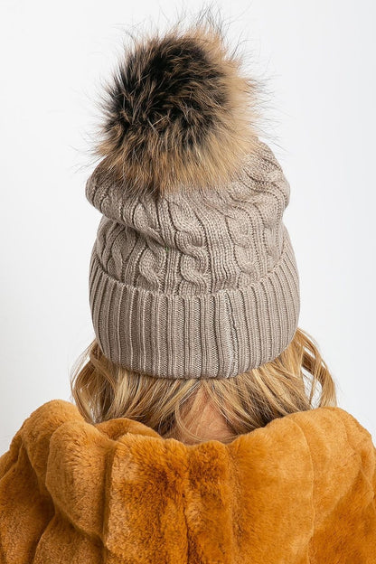 Luxury winter cap by AT featuring a wide cuff and a fluffy pompom, crafted with 50% acrylic, 30% cotton, and 20% cashmere.