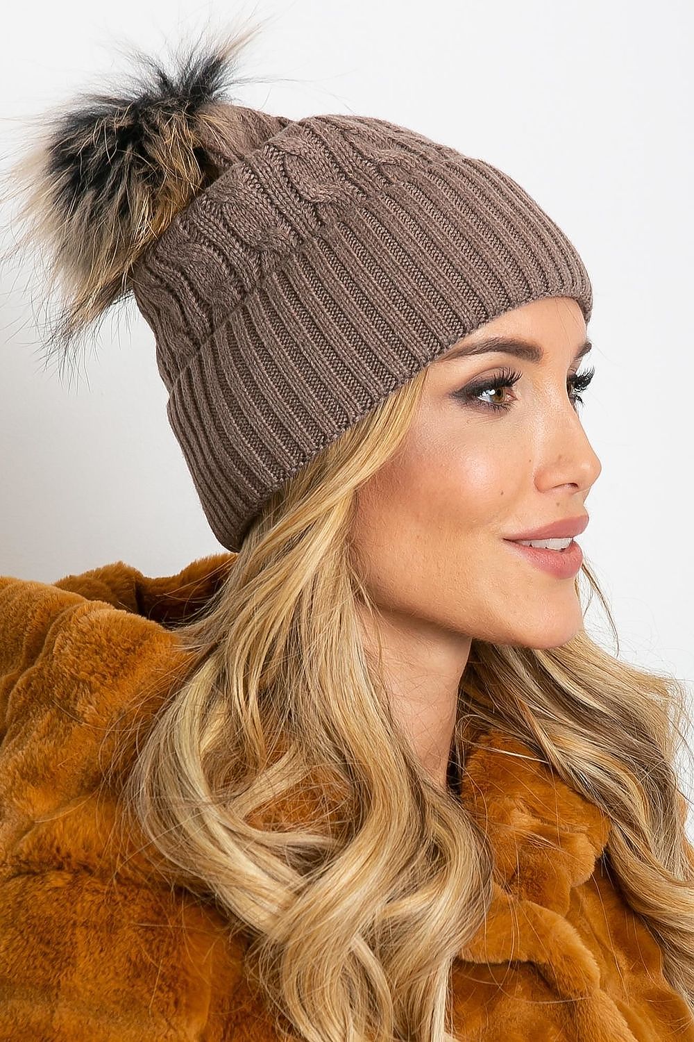 Chic luxury winter cap by AT, showcasing a plush pompom and a wide cuff, composed of a blend of acrylic, cotton, and cashmere for warmth and style.