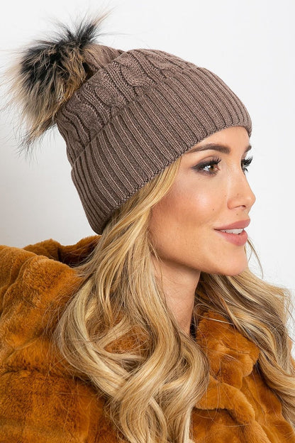 Chic luxury winter cap by AT, showcasing a plush pompom and a wide cuff, composed of a blend of acrylic, cotton, and cashmere for warmth and style.