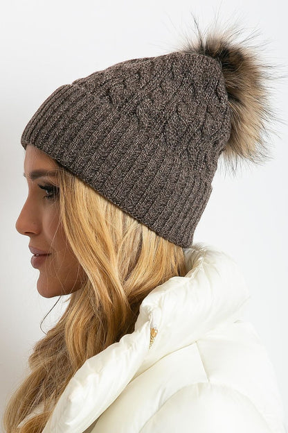 Luxurious winter cap by AT featuring a wide cuff and fluffy pompom, crafted from premium materials including acrylic, cotton, and cashmere.