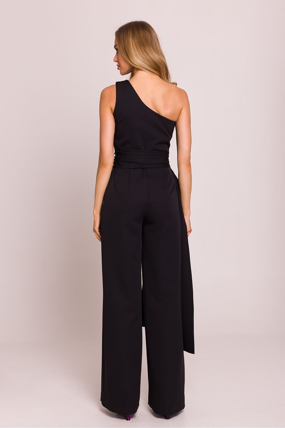 Elegant asymmetrical jumpsuit from Moe displayed on hanger, highlighting Polish craftsmanship and luxurious fabric.