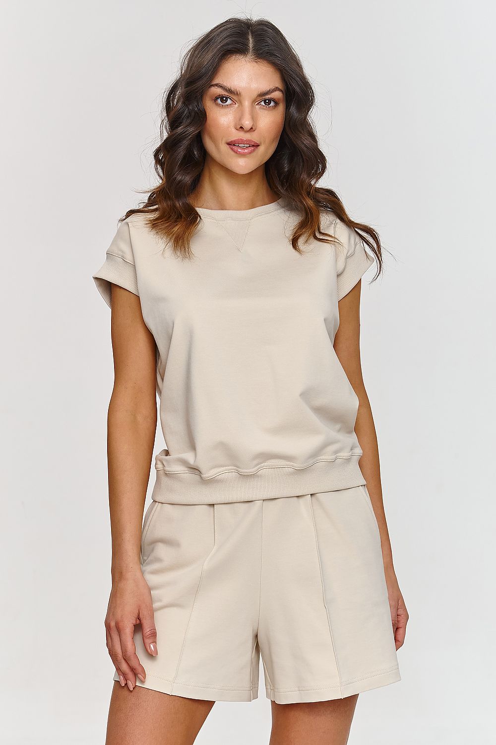 Chic Makadamia blouse designed with elastic ribbing for versatile summer wear, paired stylishly with shorts.