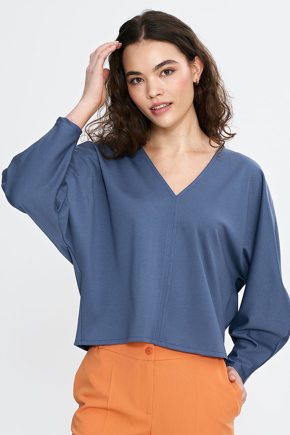 Exquisite close-up view of Nife oversized V-neck blouse showcasing the unique design of batwing sleeves and minimalist accents, made from a comfortable viscose blend.