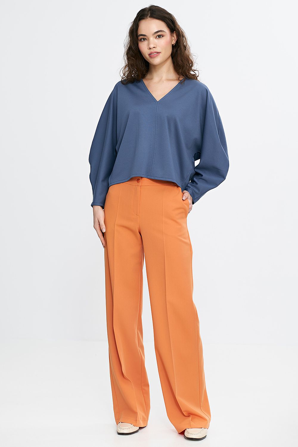 Stylish Nife oversized V-neck blouse displayed on a model, highlighting its flattering fit and sophisticated look, perfect for pairing with high-waisted bottoms.
