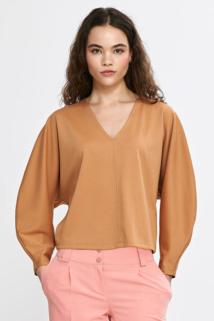 Full view of Nife's oversized V-neck blouse with a minimalist seam detail, ideal for both casual and special occasions.