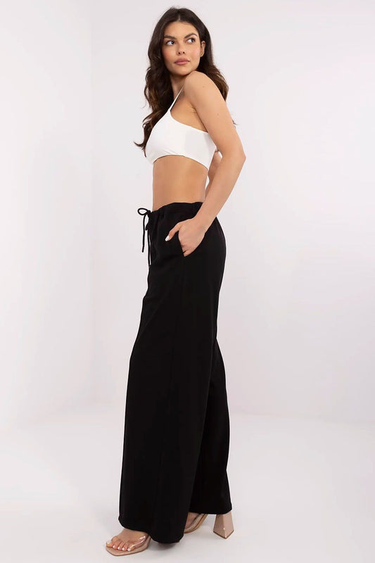 Side view of a stylish model wearing luxury black tracksuit trousers with a relaxed fit and drawstring waist, designed by Relevance for casual sophistication.