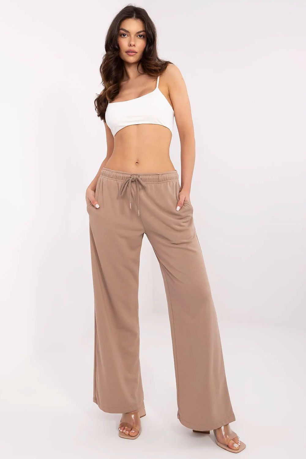 Chic front view of a model wearing luxurious cotton-blend tracksuit trousers from Relevance in a stylish beige, complementing a modern crop top.