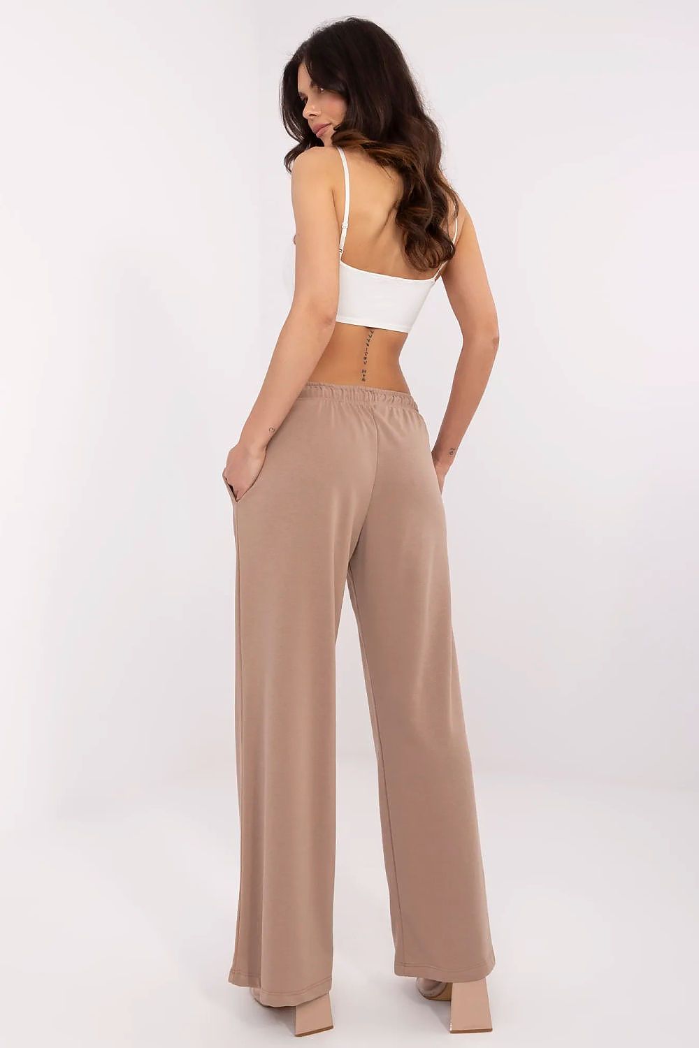Stylish back view of a model dressed in Relevance's luxurious beige cotton-blend tracksuit trousers, elegantly styled with a minimalistic crop top.