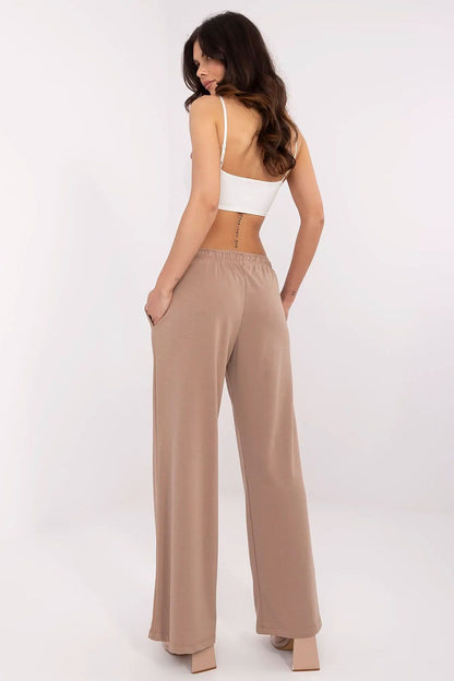 Stylish back view of a model dressed in Relevance's luxurious beige cotton-blend tracksuit trousers, elegantly styled with a minimalistic crop top.