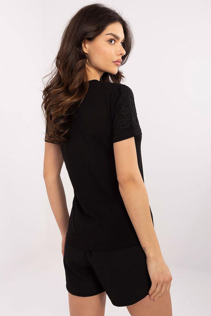 Elegant woman in a black short-sleeved casual t-shirt with unique embroidery, showcasing the stylish design from Relevance. The model is posed from the back, emphasizing the simplicity and sophistication of this soft cotton blend top.