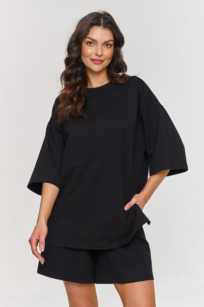 Stylish model in a classic black oversized t-shirt and shorts tracksuit set from Makadamia, designed for comfort and versatility.