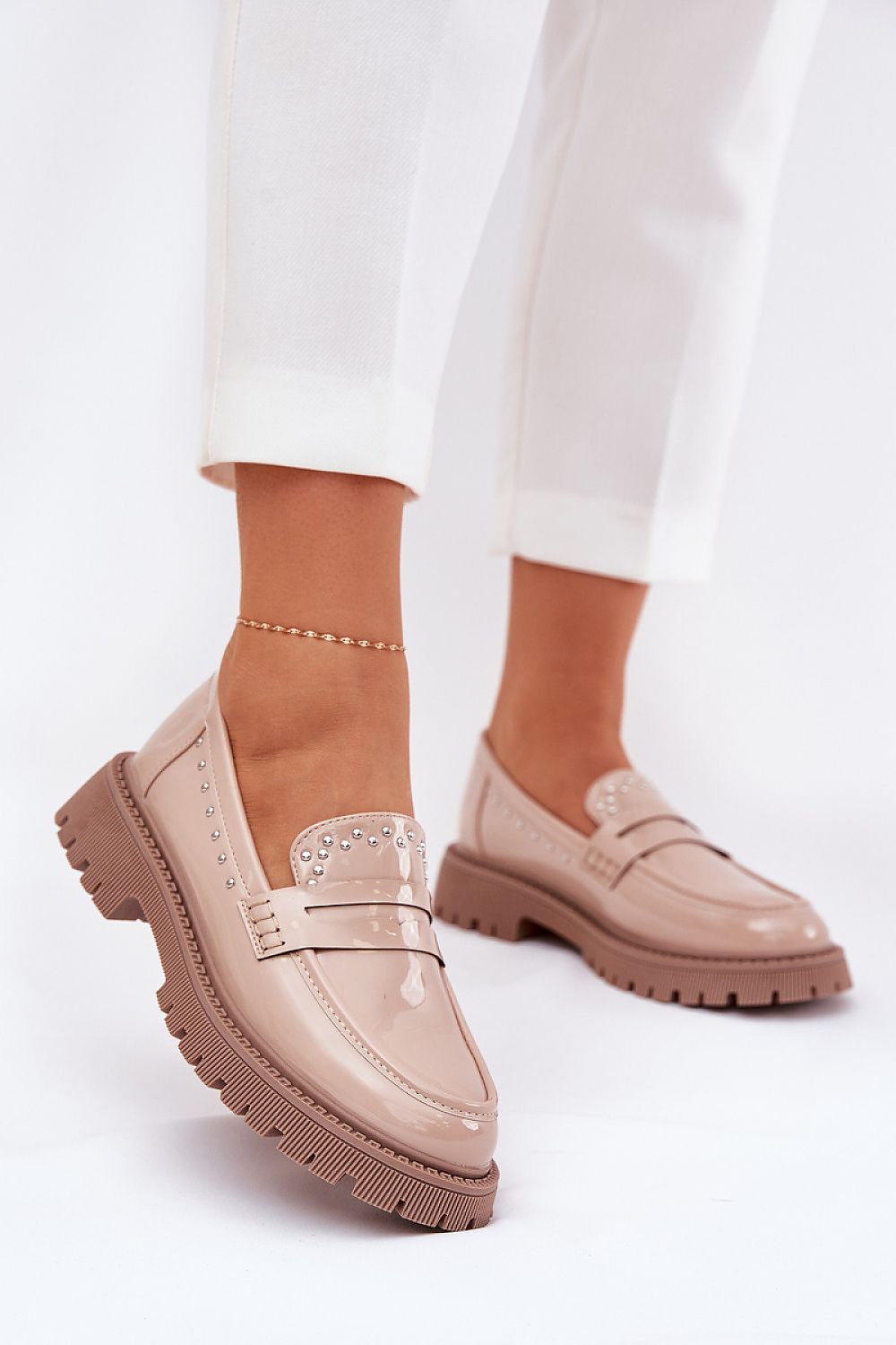 Elegant women's moccasins in patent eco leather by Step in style, featuring stylish embellishments and a flat heel, worn casually with fashionable trousers.