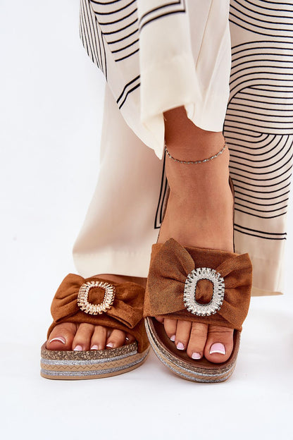 Model wearing luxury eco suede brown flip-flop slippers with bow and brooch by Step in Style, showcasing stylish summer footwear paired with a chic outfit.