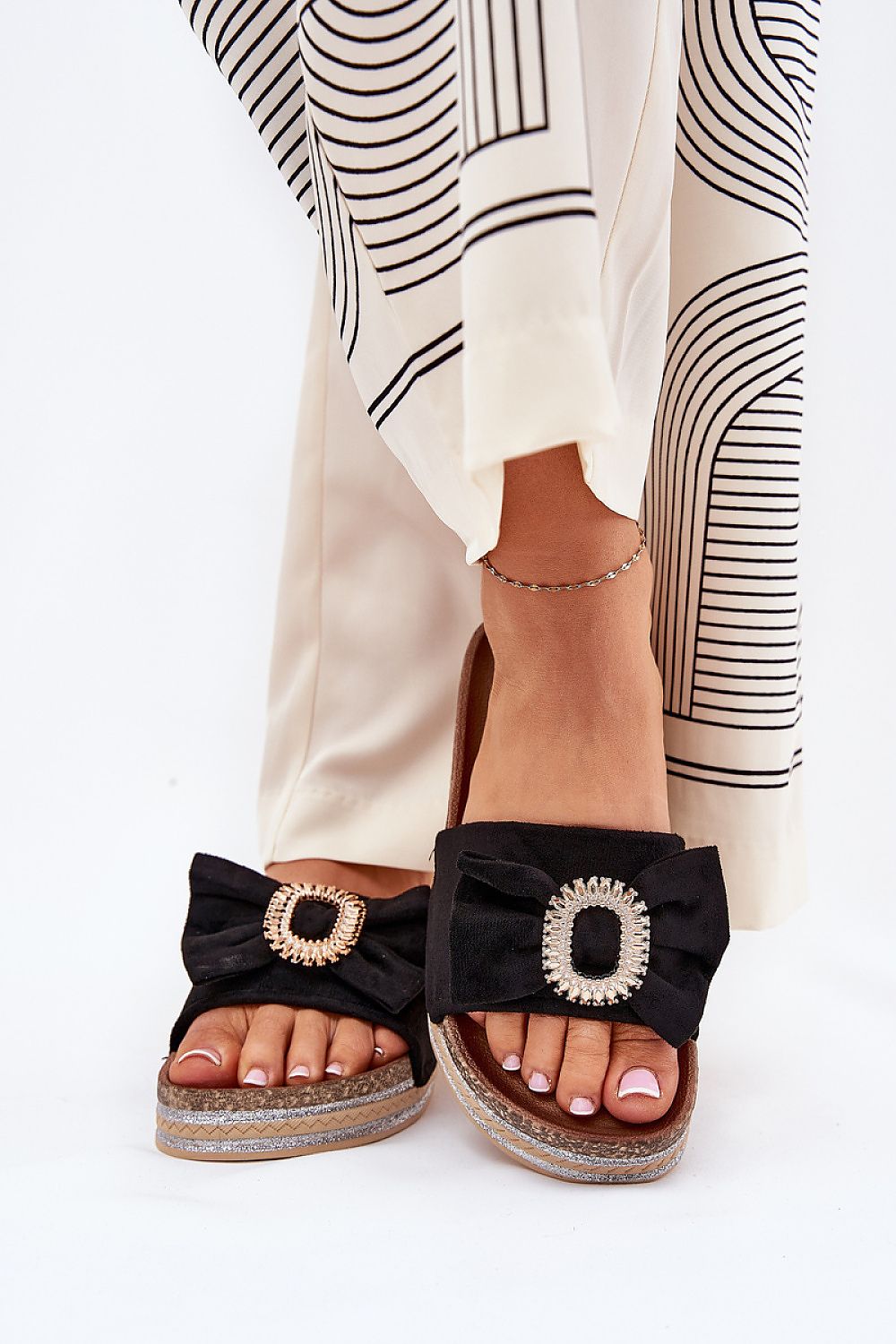 Model displaying luxury eco suede black flip-flop slippers with bow and brooch, designed by Step in Style, ideal for adding elegance to summer looks.