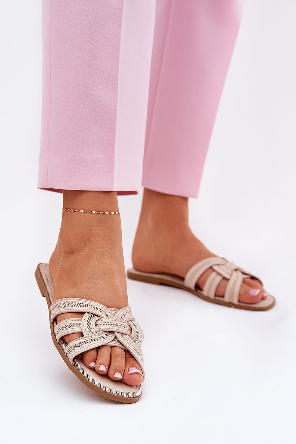 Chic beige eco leather flip-flops featuring interwoven design, styled with pink tailored trousers on a model, offered by Step in Style.