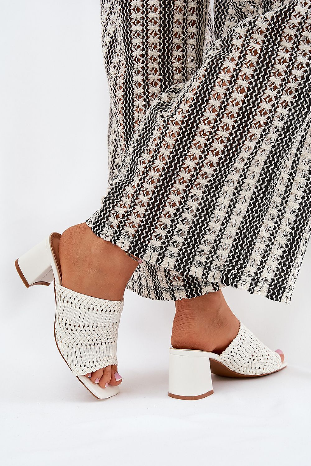 Stylish white women's slipper from Step in Style worn with flowing patterned trousers, showcasing a modern braid design and comfortable fit.