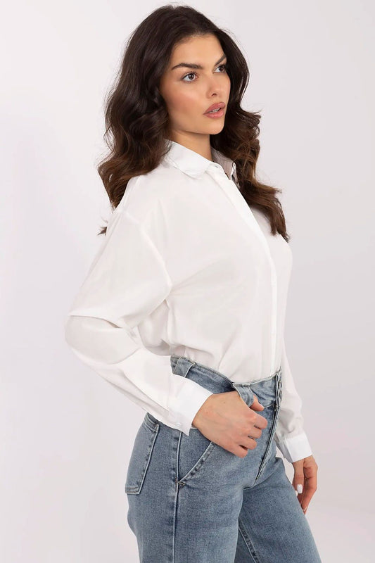 Side view of a sophisticated women's white shirt by NM, showcasing long sleeves and a polished collar, elegantly complemented by denim trousers for a chic outfit.
