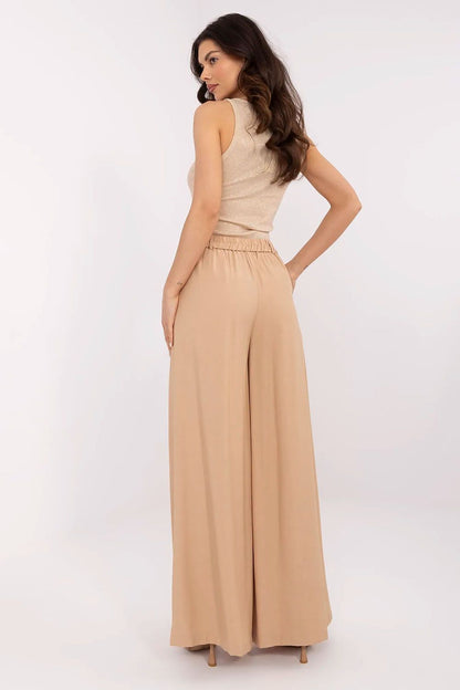 Back view of luxurious women's palazzo pants in beige, designed by NM, emphasizing a chic and flattering silhouette suitable for sophisticated outings.
