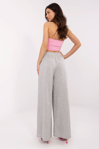 Back view of a chic woman wearing a pink strapless top and grey high-waist wide leg trousers, illustrating the stylish design by Italy Moda.
