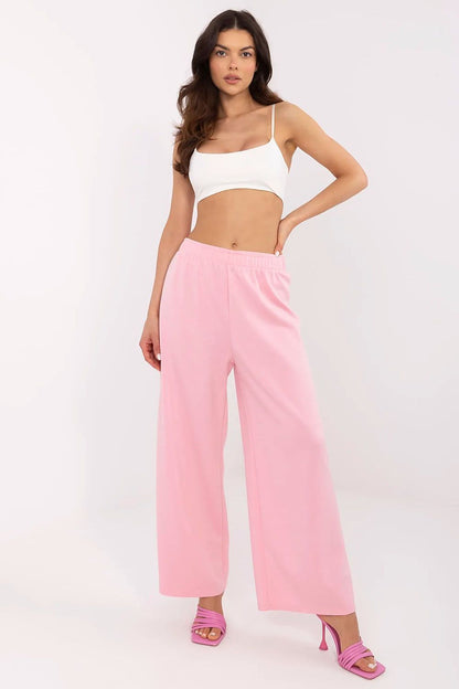 Sophisticated woman in a white crop top and pastel pink high-waist wide leg trousers, displaying the refined fashion sense of Italy Moda.