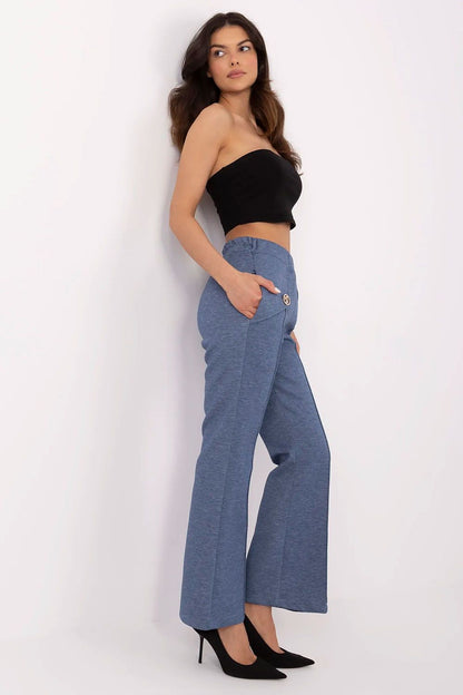 Side view of a sophisticated woman in Italy Moda high waist bell-shaped sweatpants in blue, paired with a black crop top, highlighting the pants' elegant fit and functional side pockets.