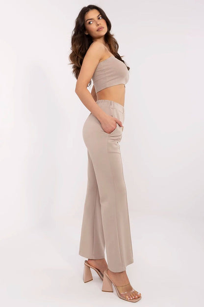 Elegant side view of Italy Moda high waist bell-shaped sweatpants in beige, featuring side pockets, paired with a stylish cropped top and high heels for a sophisticated casual look.