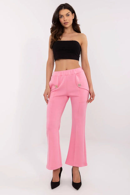 Fashion-forward front view of Italy Moda high waist bell-shaped sweatpants in vibrant pink, featuring functional side pockets and gold brooches, styled with a black crop top and elegant heels.